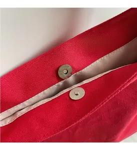 Dettaglio macro della borsa tote in tela rossa con chiusura magnetica e logo ricamato