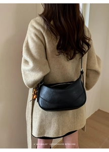 Borsa a tracolla a mezzaluna nera minimalista con ciondolo in legno indossata