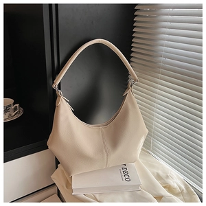 Détail du sac bandoulière croissant beige montrant le grain de cuir et le zip métal