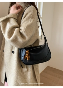 Detail of retro black leather crescent bag featuring unique wooden bead zipper charm