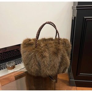 Nahaufnahme einer dunkelbraunen Plüschtasche mit detailreichen Leder-Flechtgriffen