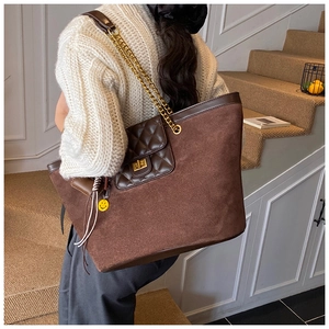 Brown tote bag detail with diamond quilted flap pocket and yellow smiley pendant charm