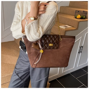 Detail of dark brown suede tote bag with diamond lattice leather flap and gold twist lock