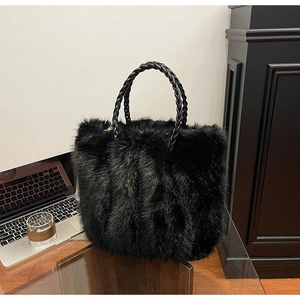 Detail einer schwarzen Kunstpelz-Tasche mit geflochtenen Ledergriffen in Büro-Atmosphäre