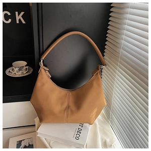Détail de la texture cuir de litchi caramel et de la forme incurvée de ce sac chic