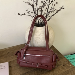 Detailed view of the dark red faux leather shoulder bag with silver zippers and side pockets