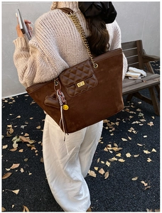 Detail of deep brown suede tote bag with diamond quilted flap and gold metal twist lock