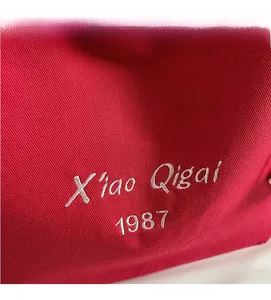 Primo piano della borsa in tela rossa che mostra la trama fitta e il ricamo bianco inciso