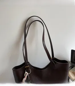 Close-up of deep brown tote bag featuring comfortable shoulder straps and gold logo detail
