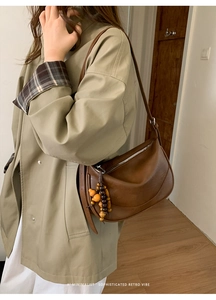 Dettaglio di borsa a mezzaluna marrone vintage con nappina di perline e tracolla regolabile