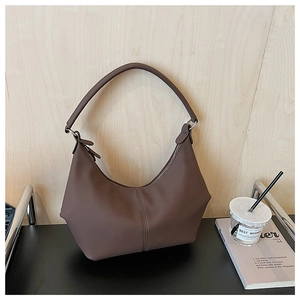 Détail d'un sac croissant en cuir marron foncé avec couture verticale et fermeture éclair