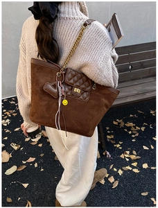 Detail of vintage brown suede tote bag with diamond quilted flap and chain strap on shoulder