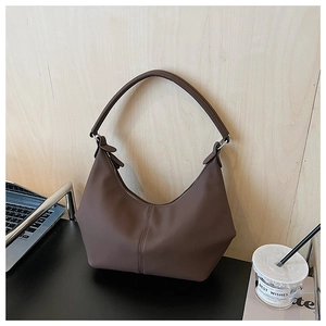 Sac hobo marron minimaliste en forme de croissant avec boucles argentées dans un bureau moderne