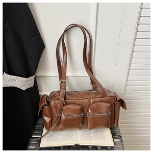 Detail of vintage brown shoulder bag with multiple zippered pockets on a suitcase