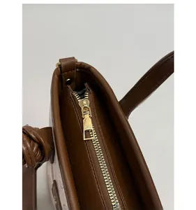Detail of premium gold metal zipper and smooth leather trim on a cartoon bucket bag