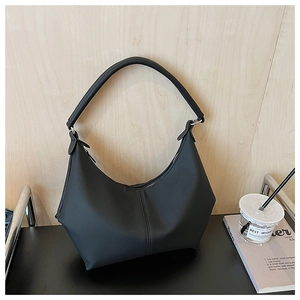 Détail d'un sac à bandoulière noir en forme de croissant avec coutures sur cuir mat