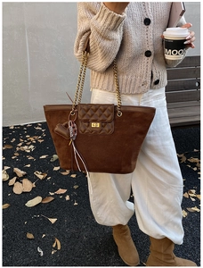 Detail of suede and leather tote bag featuring diamond pattern flap and gold lock