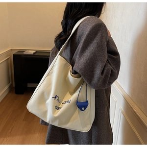 Dettaglio borsa tote in tela con borsellino in pelle blu e logo Xiao Quai 1987 stampato