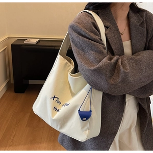 Dettaglio della borsa tote in tela bianca con scritte blu e piccola pochette abbinata