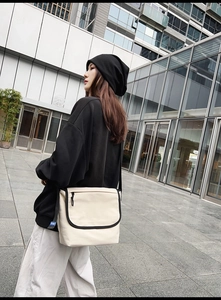 Dettaglio di una borsa a tracolla in tela crema minimalista con bordo nero e cinturino