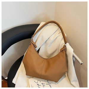 Détail du sac hobo marron avec texture grainée et forme demi-lune sur une chaise