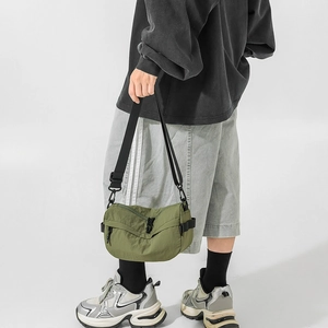 Sac bandoulière demi-lune en nylon vert armée porté avec une tenue décontractée chic