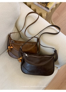 Close-up of vintage brown shoulder bags with wooden bead charms and textured matte leather