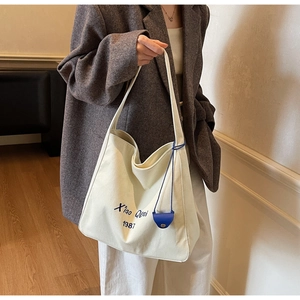 Elegante borsa tote in tela beige con stampa di lettere e portamonete blu sul modello