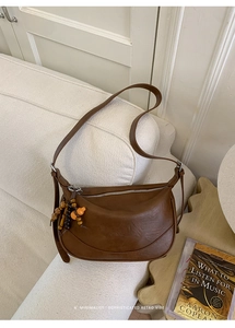 Dettaglio della borsa hobo retrò marrone con nappe di perline bohémien su divano in tweed