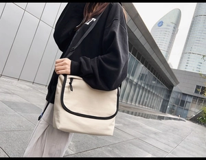 Dettaglio della tracolla nera regolabile di una borsa a tracolla in tela color crema