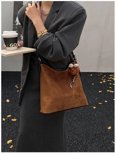 Close-up of brown suede tote bag featuring a cute bear charm in an autumn outdoor setting