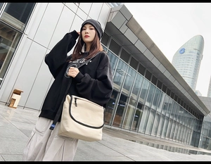 Dettaglio borsa messenger in tela beige con finiture nere e tracolla regolabile