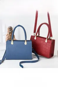 Detail view of crocodile-patterned handbags with woven handles and golden metal accessories
