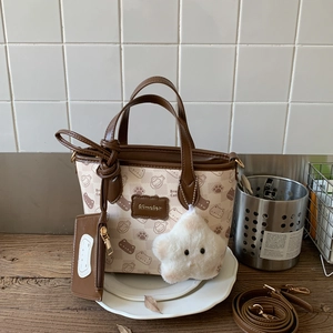 Detail view of mini canvas tote with cute cat prints, brown PU handles and plush star charm