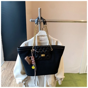 Detail of black tote bag featuring gold chain strap and quilted front pocket with twist lock