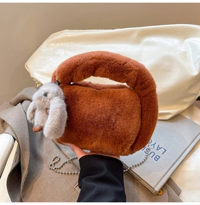 Detail of soft plush puppy shaped handbag with a metal ball chain strap for crossbody wear