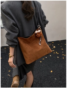 Brown vintage suede tote bag with cute bear charm shown in an outdoor autumn setting