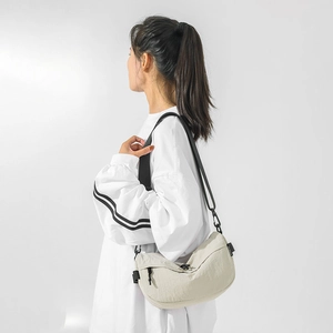 Détail du sac bandoulière croissant blanc cassé en nylon avec sangle noire réglable