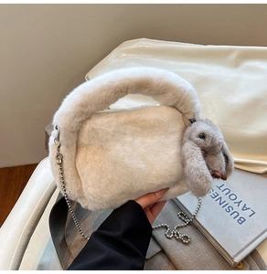 Detailed texture of fluffy beige faux rabbit fur handbag with cute bunny pendant and silver chain