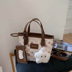 Detail of cartoon print tote bag with brown handles and a plush star pendant on a black mat