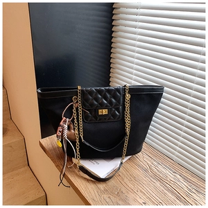 Detail of black tote bag with quilted leather flap, gold chain strap and side charm