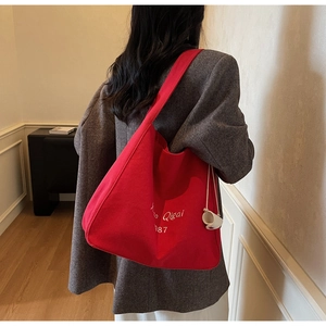 Vista posteriore dettagliata di una grande borsa tote in tela rossa con ricamo sul modello