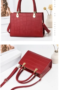 Detail of red crocodile texture handbag featuring woven handles and gold metal hardware