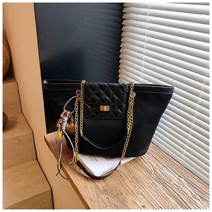 Close-up of black tote bag featuring quilted leather flap and golden chain strap detail