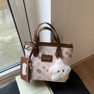 Detail of cartoon bread cat tote bag with small pouch and plush star charm on a desk