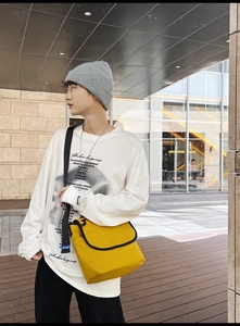 Scatto all'aperto di borsa a tracolla in tela giallo brillante con stile urbano bianco