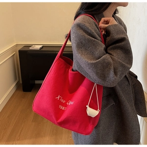 Dettaglio della borsa tote in tela rossa con ricamo bianco e mini custodia inclusa