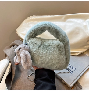 Detail of sage green plush handbag featuring a rabbit charm and silver ball chain strap