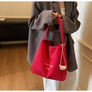 Dettaglio della borsa tote in tela rossa con ampia tracolla e mini astuccio decorativo