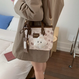 Detail of cartoon print shoulder bag featuring leather straps and plush star accessory